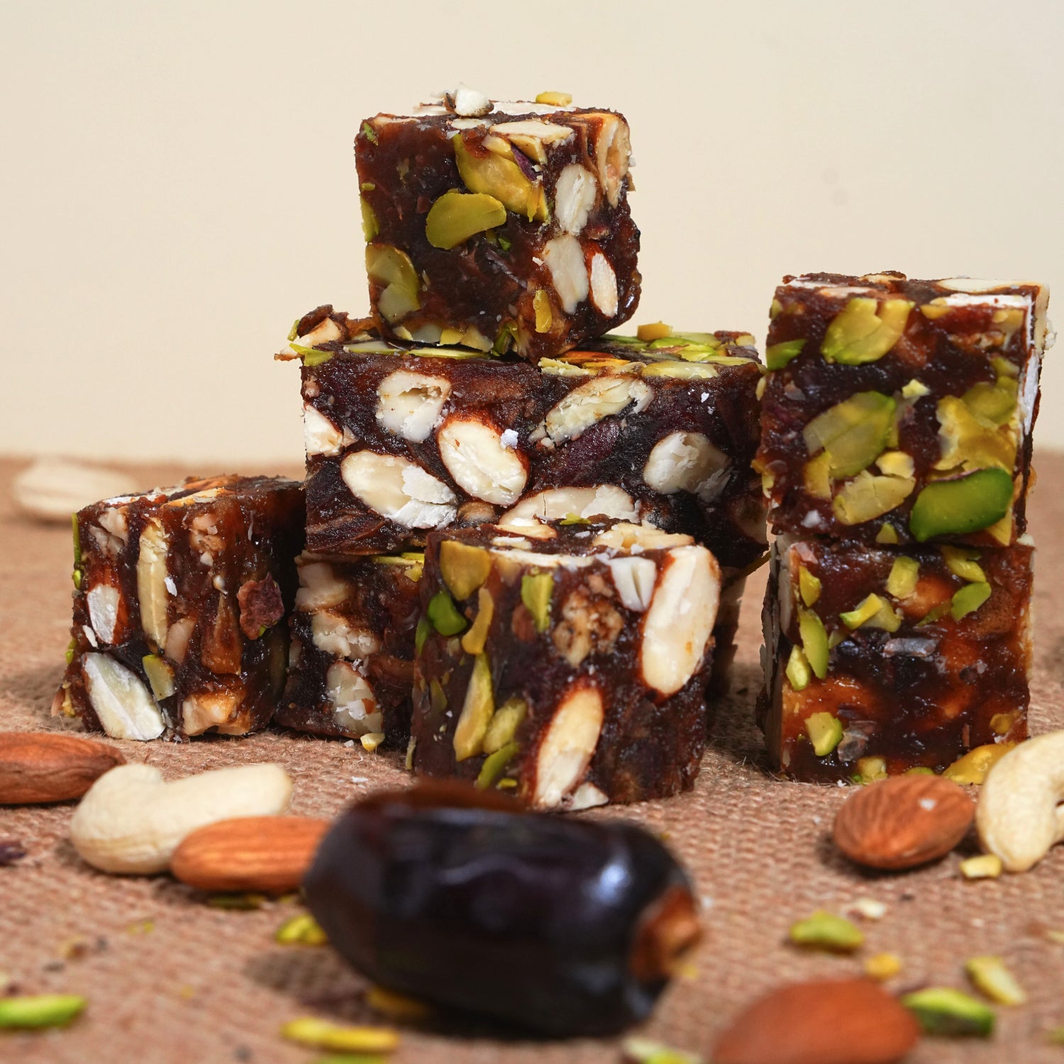 Stack of nut and seed bars with dates and almonds on a wooden surface