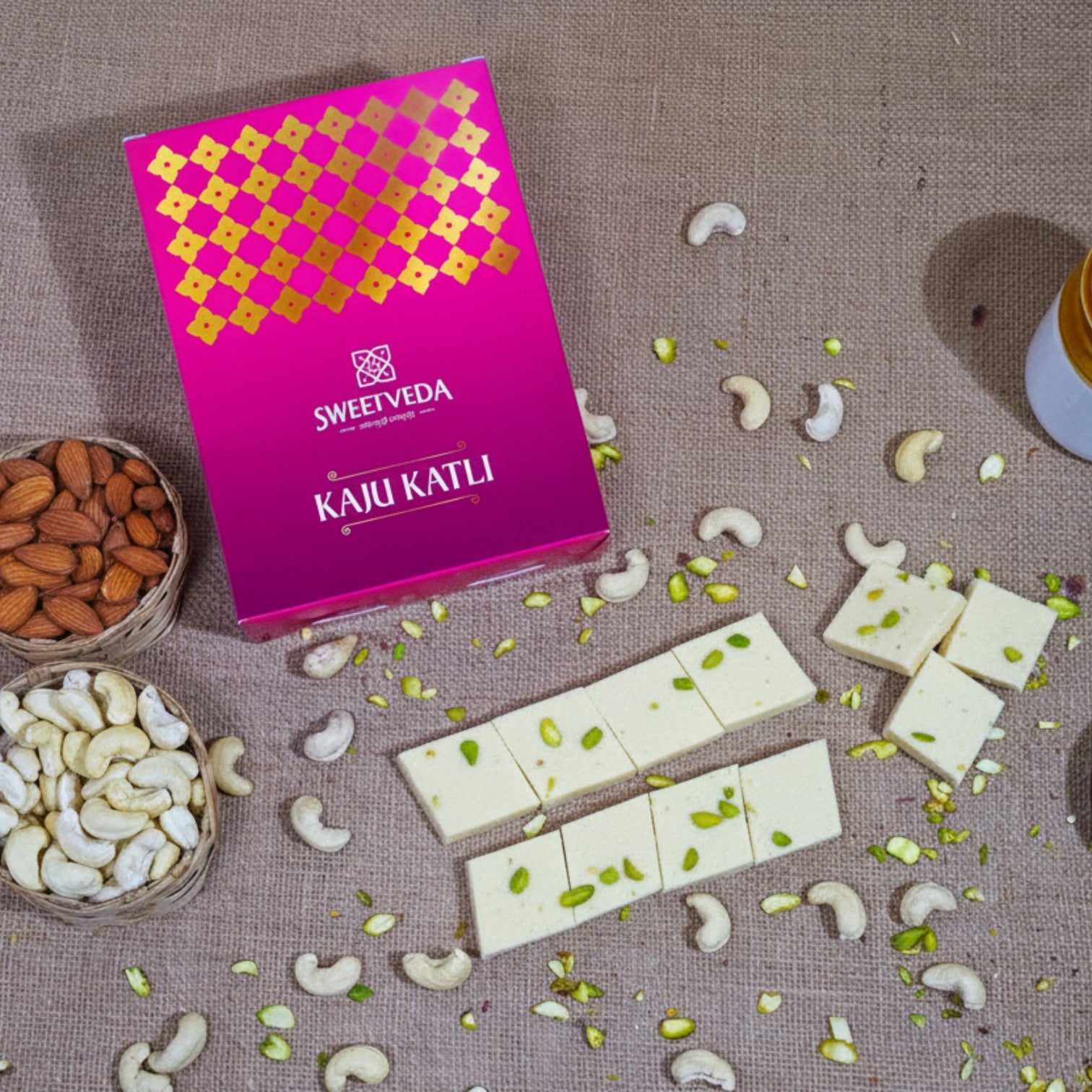 Sweetveda Kaju Katli with cashew nuts and almonds on a textured surface